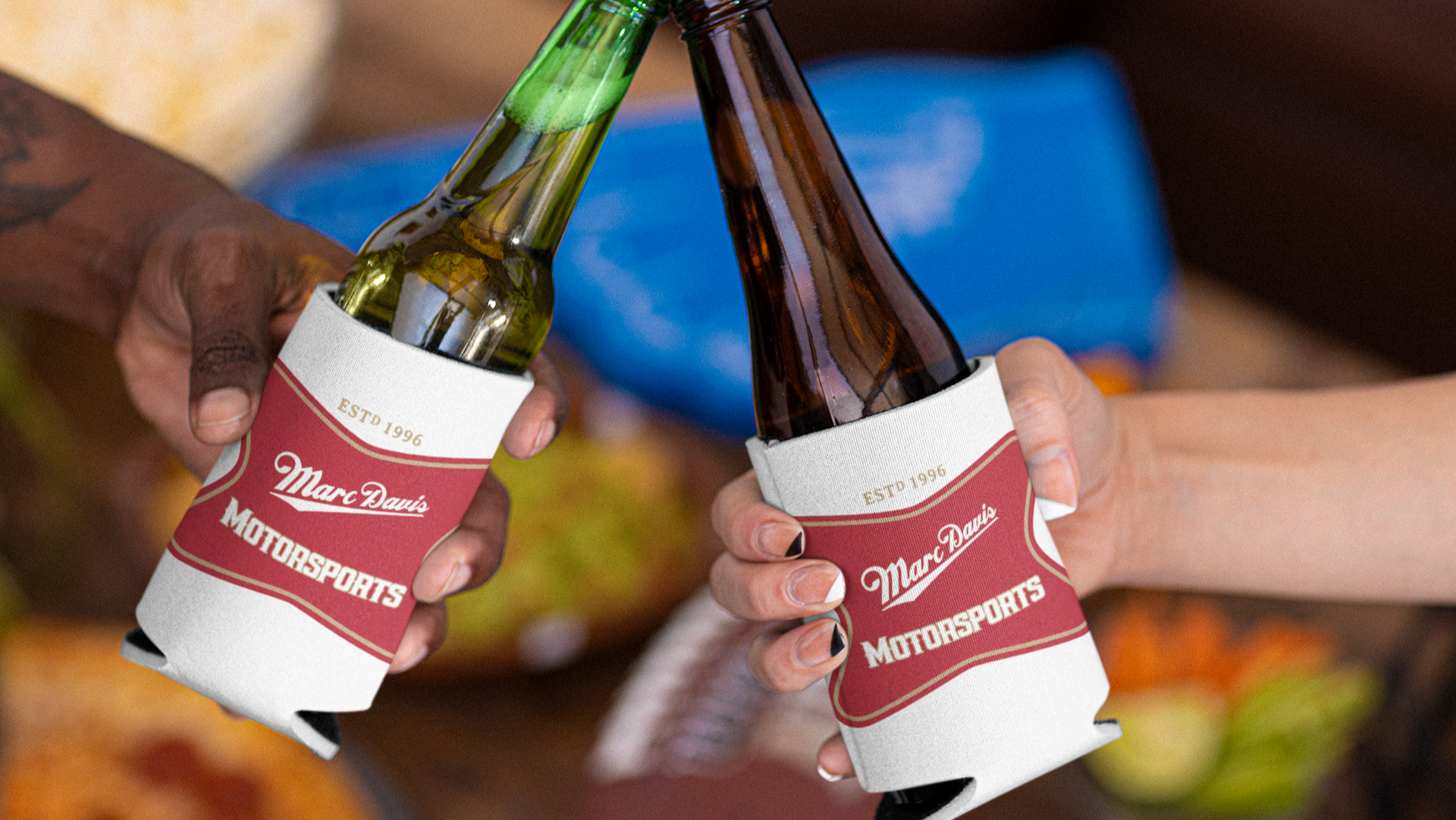 Two people toasting with Marc Davis Motorsports koozies on glass bottles.
